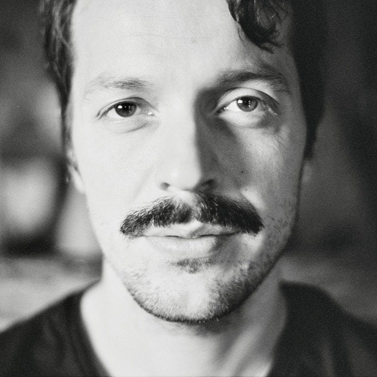 Rođen sam na Kosovu. Moja porodica je izbegla u Švajcarsku zbog mog oca. Bio je politički aktivan i zatvoren zbog svog aktivizma — morali smo da pobegnemo kako su tenzije rasle devedesetih. A zatim sam u Švajcarskoj vodio klasičan migrantski život.<br />
Dok sam učio IT u Švajcarskoj, shvatio sam da me zapravo privlači dizajn. Volim vizuelne stvari, svetlost. Ali dugo nisam znao da je moguće studirati film. Mislio sam da samo privilegovani ljudi mogu praviti filmove — oni koji imaju mnogo novca. Nisam sebe video u tome, jer sam mislio da to nije moguće — dok nisam saznao da zapravo možeš to da studiraš. I to je postao moj cilj.